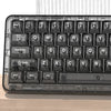 A close-up view of a black mechanical keyboard with crystal clear RGB keycaps resting on a wooden surface.
