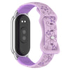 A purple silicone watch band with a silver casing and black face, featuring engraved flowers.