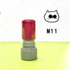 A red and gray teacher stamp with an owl face design is shown on a yellow surface.