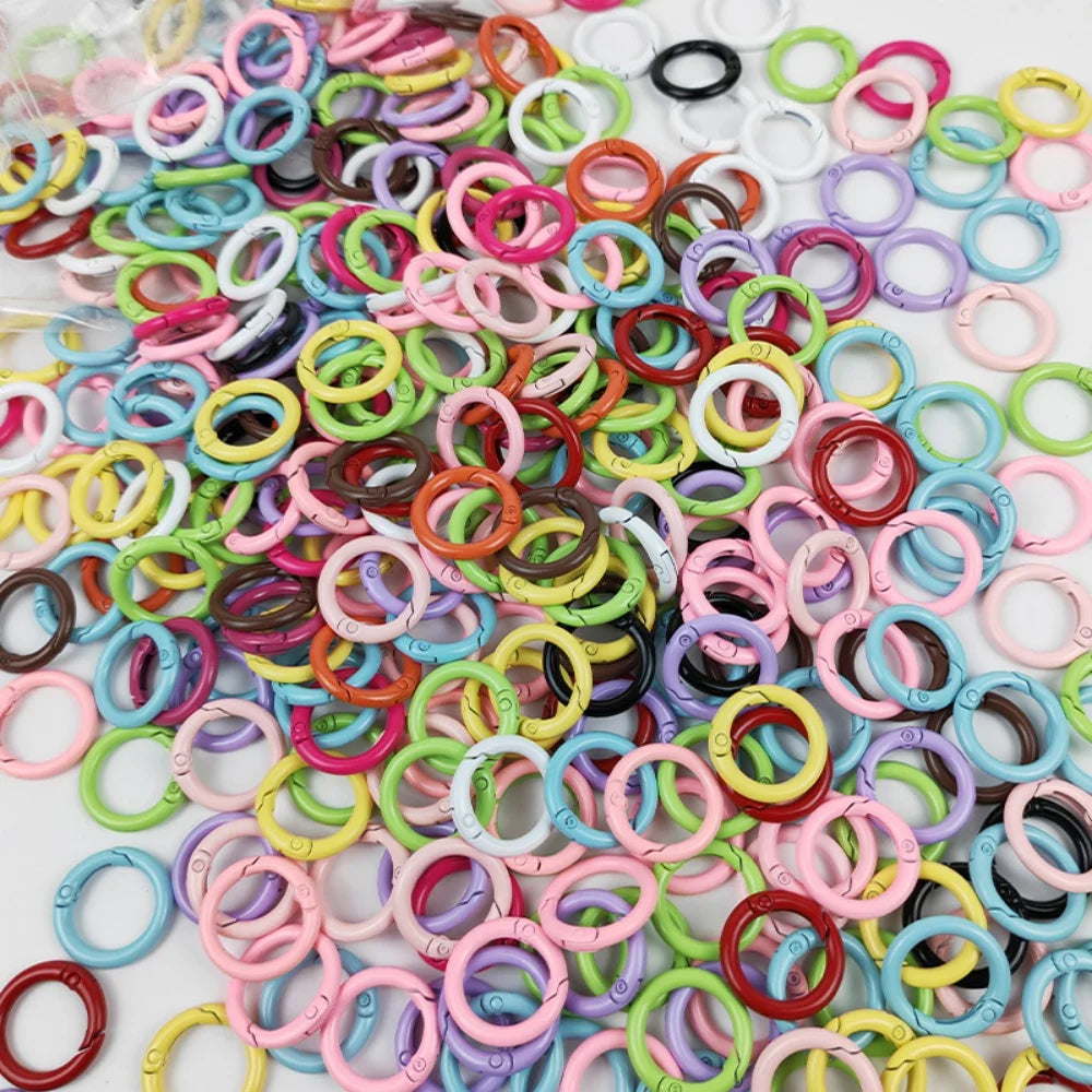 A collection of colorful spring clasps and rings in various shades of pink, green, yellow, purple, and black.