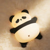 A cute panda silicone night light with touch control and USB rechargeable illuminating a fluffy white surface.