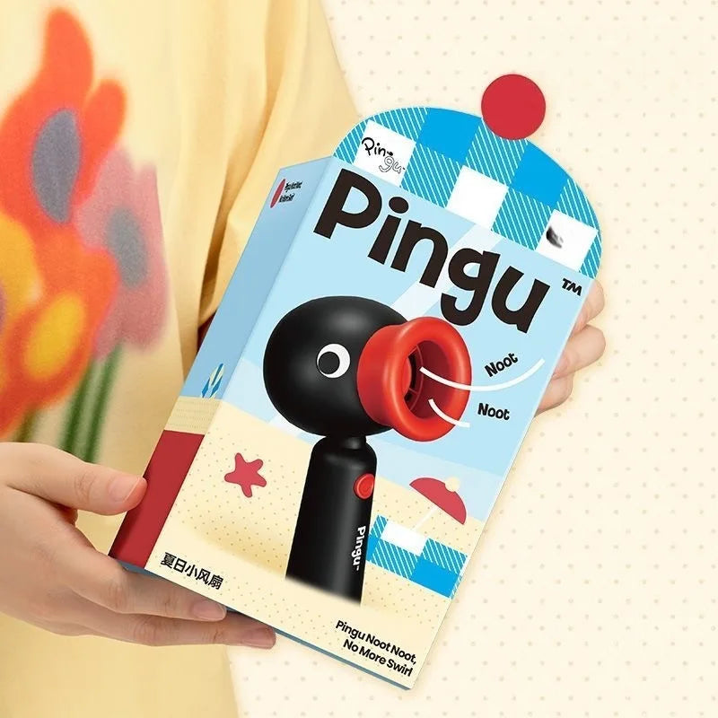 A hand holds a Pingu penguin rechargeable handheld fan with a rotating head against a light background.