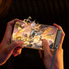 Hands hold a foldable charging cable with an integrated stand, demonstrating its use for game controls.