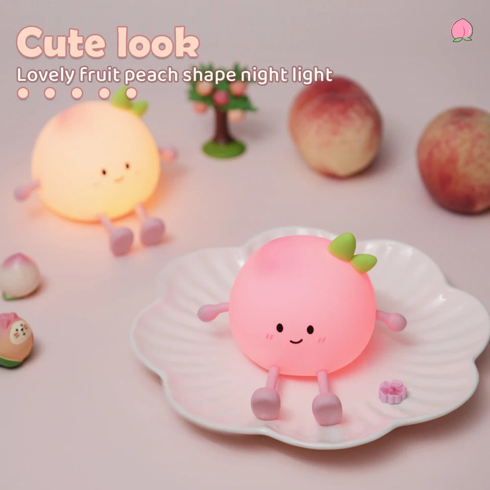 A pink, peach-shaped night light illuminates a fruit replica on a white plate surrounded by various fruit shapes.