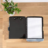 A black A4 waterproof file box with a writing board and pen slot is shown on a wooden table next to a potted plant.