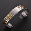 Stainless steel watch band with gold accents and a folding safety clasp shown on a dark background.
