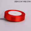 A roll of red satin ribbon with a white center core is shown on a white background.
