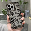 A hand holds a clear phone case with a black floral pattern and multiple camera lenses.