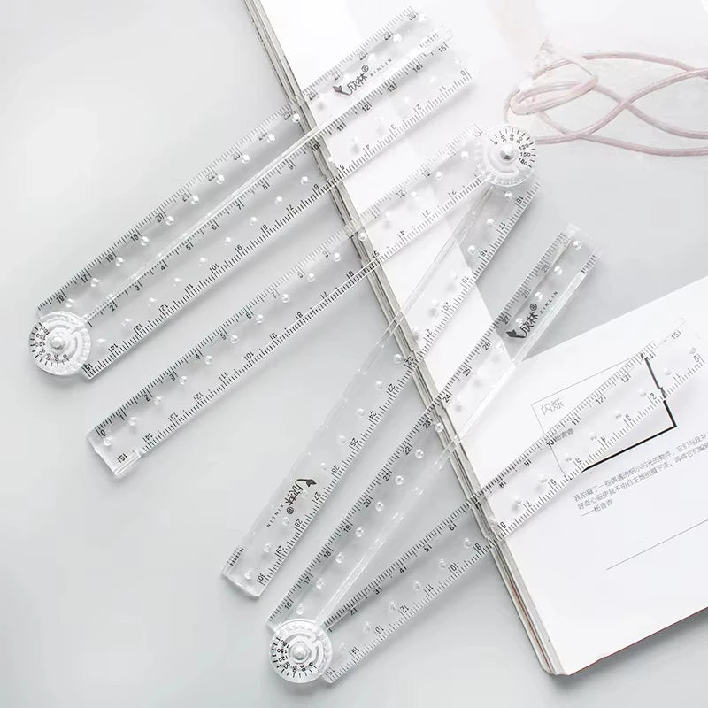 A set of precision folding transparent rulers and measuring tools laid out on a white background.