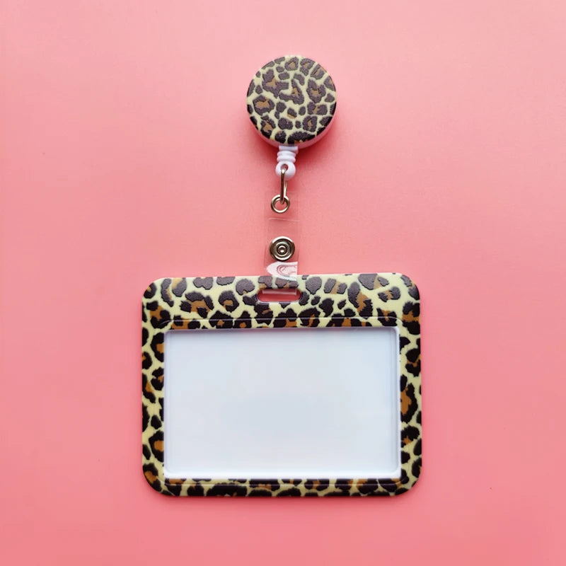 A leopard print ID holder with a clear plastic frame and a matching lanyard keychain on a pink background.