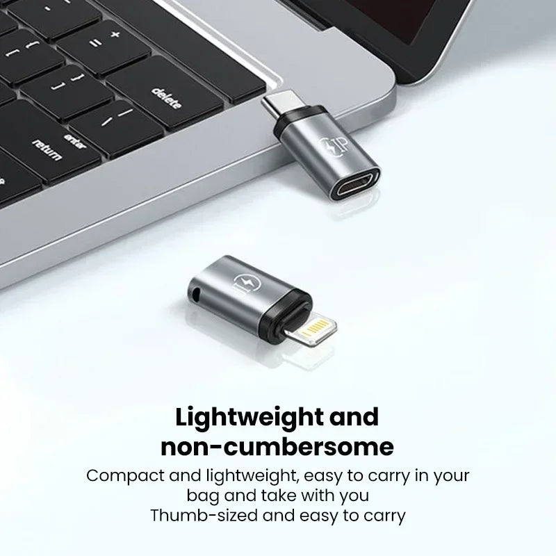 Silberlaptop-Tastatur mit Lightning-auf-USB-C-Adapter und USB-Stick auf weißer Fläche.