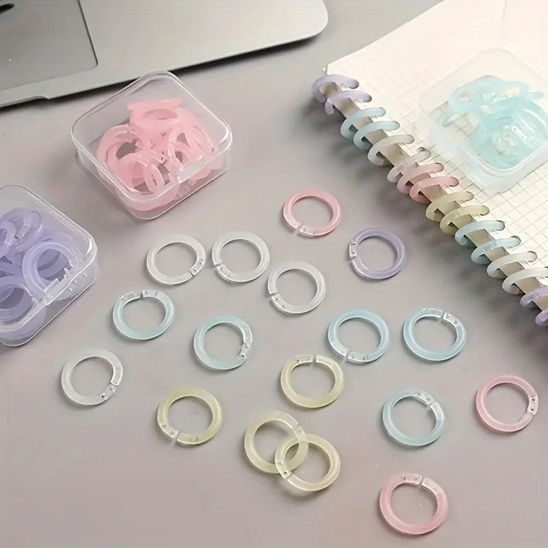 A collection of colorful reusable plastic binding rings in various shades of pink, blue, and clear are displayed on a light s