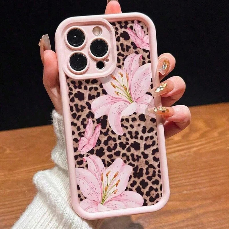 A pink leopard print phone case with a floral design is held by a hand.