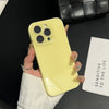 A hand holds a yellow iPhone in a clear case against a black background next to a white box.