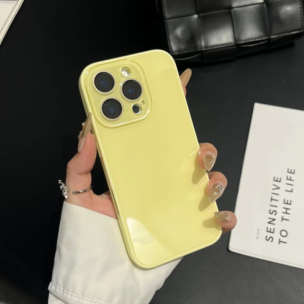 A hand holds a yellow iPhone in a clear case against a black background next to a white box.