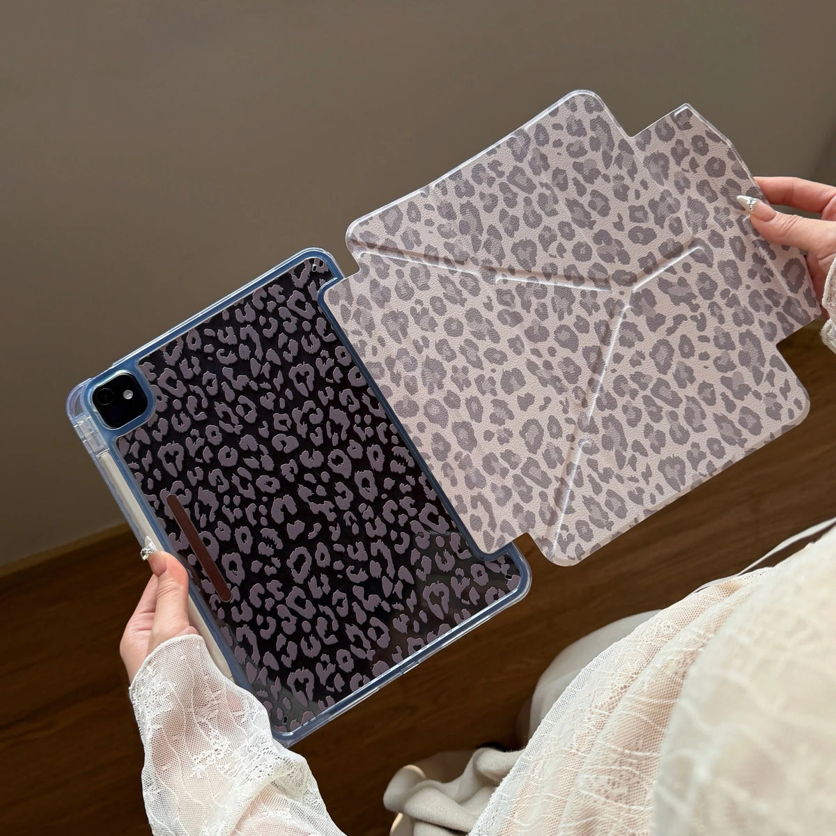 A hand holds a clear leopard print leather case for an iPad, showing the textured pattern.