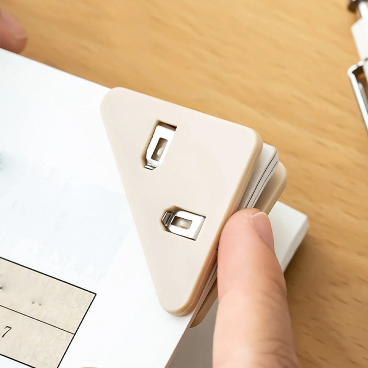 A hand is clipping a document folder using a multifunctional triangle clip for documents.