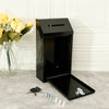 A black wall-mounted metal drop box with a lock and key resting on a gray surface.