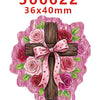 A wooden cross decorated with pink and red roses and leaves, set against a pink background.