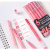 A set of Languo 90-Color Acrylic Gel Pens in various shades, including pink and red, displayed on a spiral notebook.