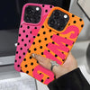 A hand holds an orange and pink polka dot phone case with the letter S and G printed on it.