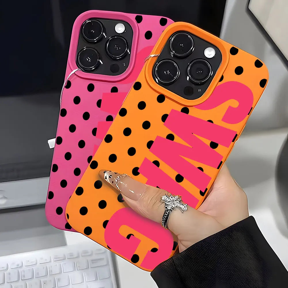 A hand holds an orange and pink polka dot phone case with the letter S and G printed on it.