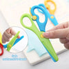 A hand is holding a green and blue two-tone plastic scissor, demonstrating its safe use for crafting.