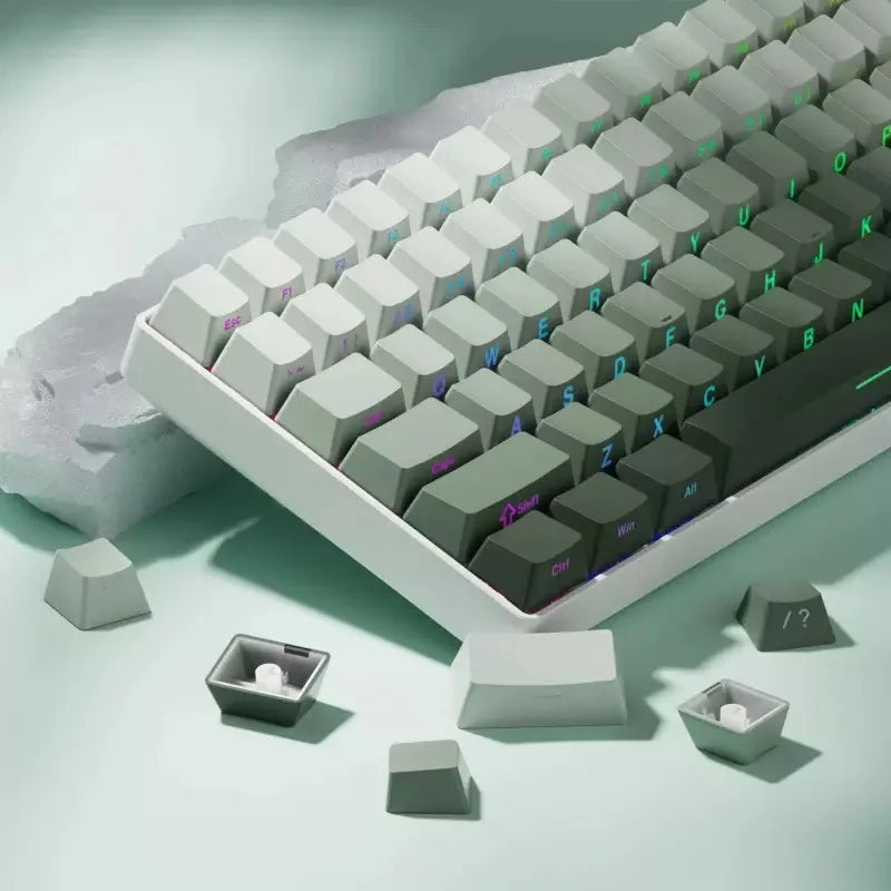 Vista cercana de un teclado mecánico blanco con teclas grises e iluminación RGB verde sobre una superficie clara.