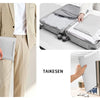 Ein beigefarbener Laptop-Sleeve wird von einer Person getragen, zusammen mit einem grauen Koffer voller anderer Gegenstände u