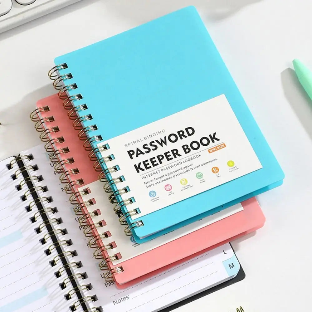 A teal spiral-bound password keeper book with pink and white pages resting on a white surface.