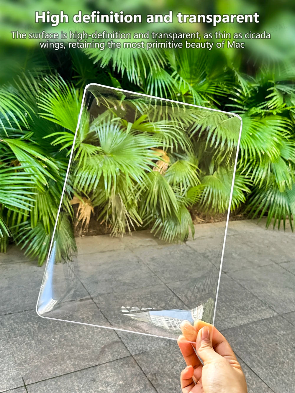 Ein durchsichtiges Acryl-Laptop-Schutzetui wird über üppiges grünes tropisches Laub gehalten.