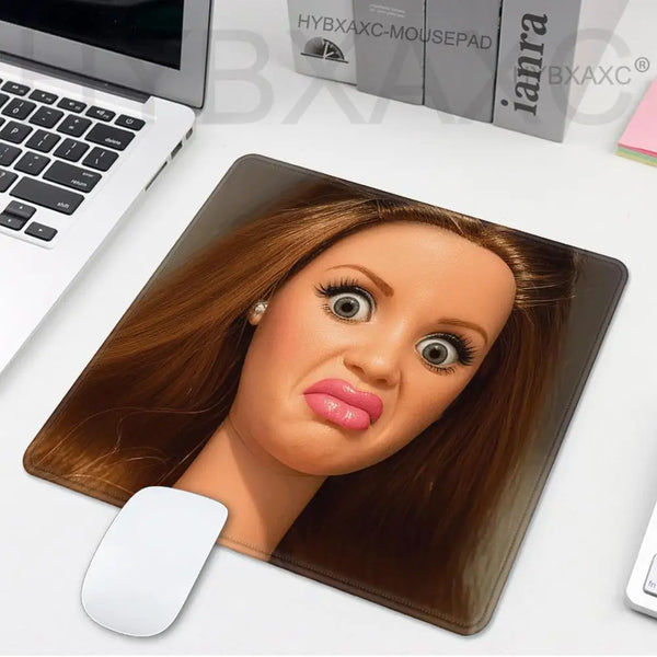 A realistic doll face print on a leather mouse pad with a white mouse underneath.