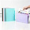 A purple accordion folder with a teal cover and a white card being pulled out by a hand.