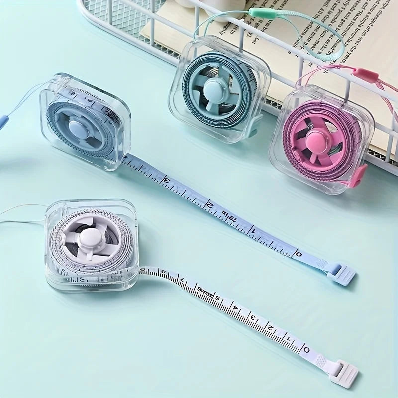 A clear plastic retractable measuring tape with a fan-like head is shown next to a notebook.