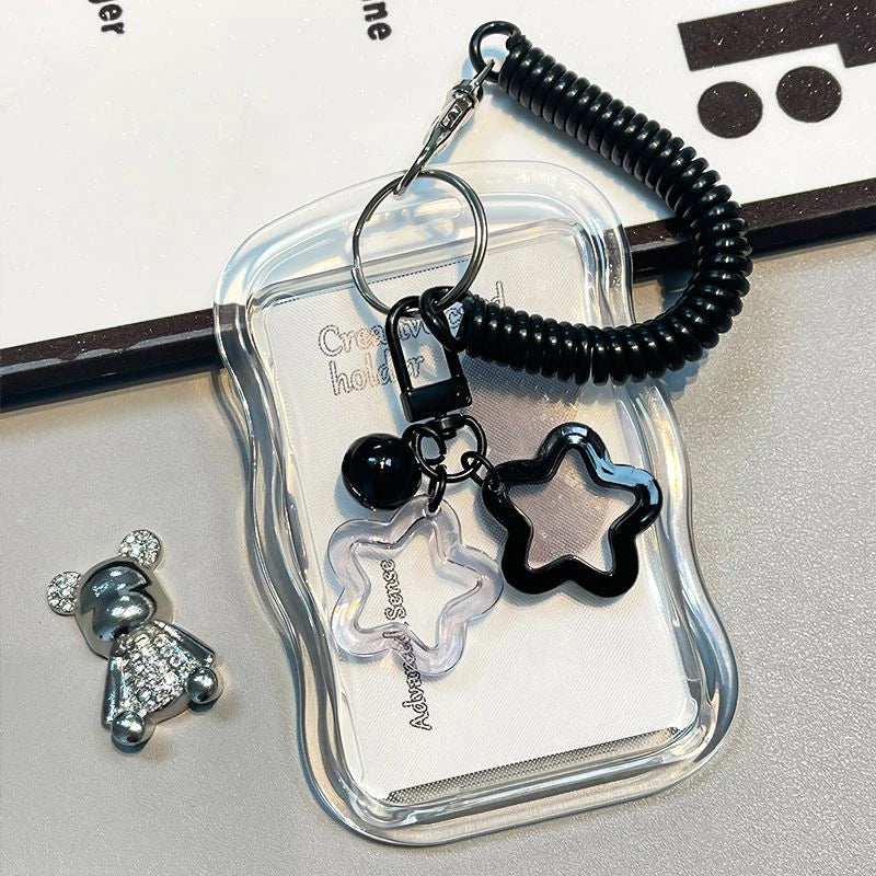 A clear plastic card holder with a black beaded keychain featuring a star charm and a small silver animal figure.