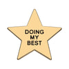 A gold star-shaped enamel pin with the text Doing My Best engraved on it.