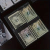 A close-up view of several US dollar bills and envelopes laid out on a dark surface.