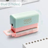 A light green mini multi-hole punch with a pink casing and silver punch, shown next to a stack of paper.