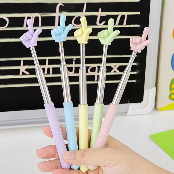 A hand holds several stainless steel teaching pointer sticks with various colored grips and hand signs against a black chalkb