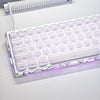 A close-up of a white mechanical keyboard with translucent purple and pink keycaps, illuminated by RGB lighting.