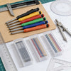 A collection of colorful refillable woodworking marker pencils arranged on a wooden board next to rulers and drafting tools.