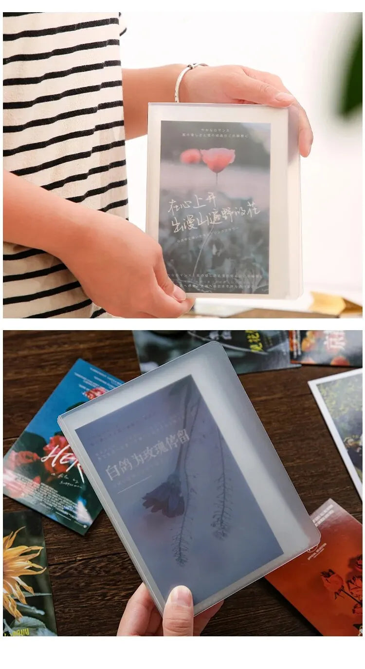 A hand holds an A6 photo storage booklet with a dark cover featuring delicate floral imagery.