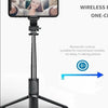 A black selfie stick tripod with a smartphone mounted, featuring a fill light and wireless remote control.