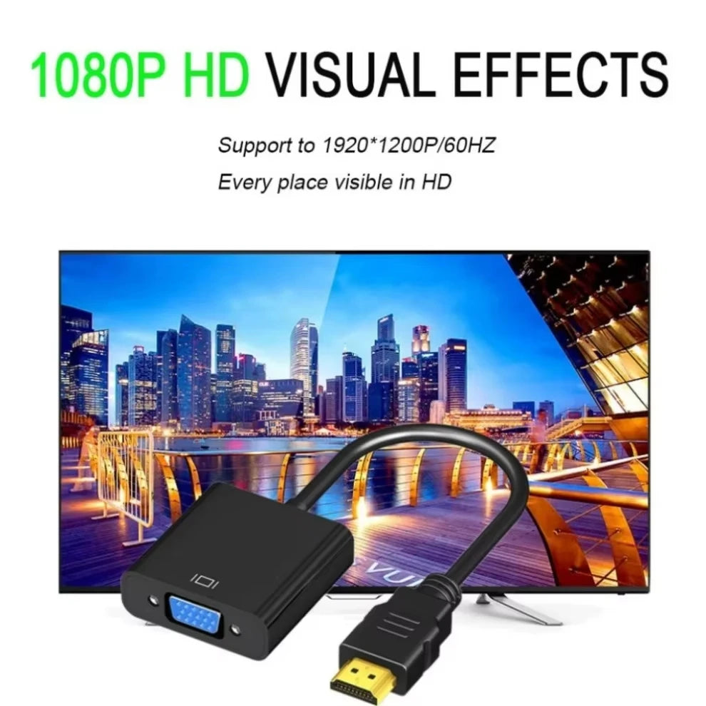 Black HDMI to VGA adapter cable with a yellow connector lying on a desk next to a computer monitor.