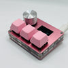 A close-up view of pink magnetic rapid trigger keyboard switches with silver top caps and a black switch visible.