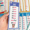 Eine Hand hält eine lila Phonics-Karte, die den Diphthong 'aw' mit Wörtern wie paw, raw, claw und awful zeigt.