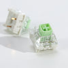A clear plastic tactile clicky mechanical keyboard switch with a green housing and white mounting base.