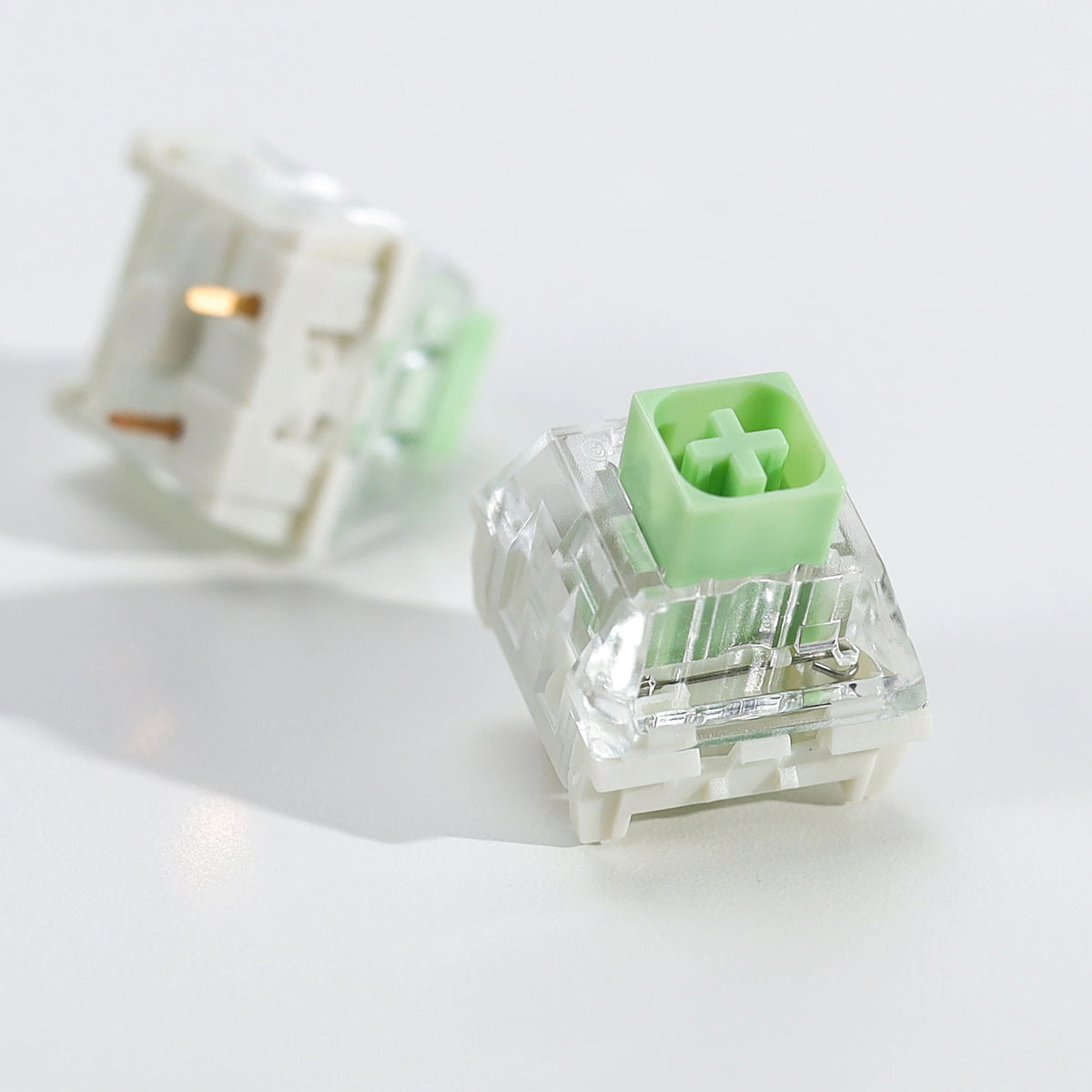 A clear plastic tactile clicky mechanical keyboard switch with a green housing and white mounting base.