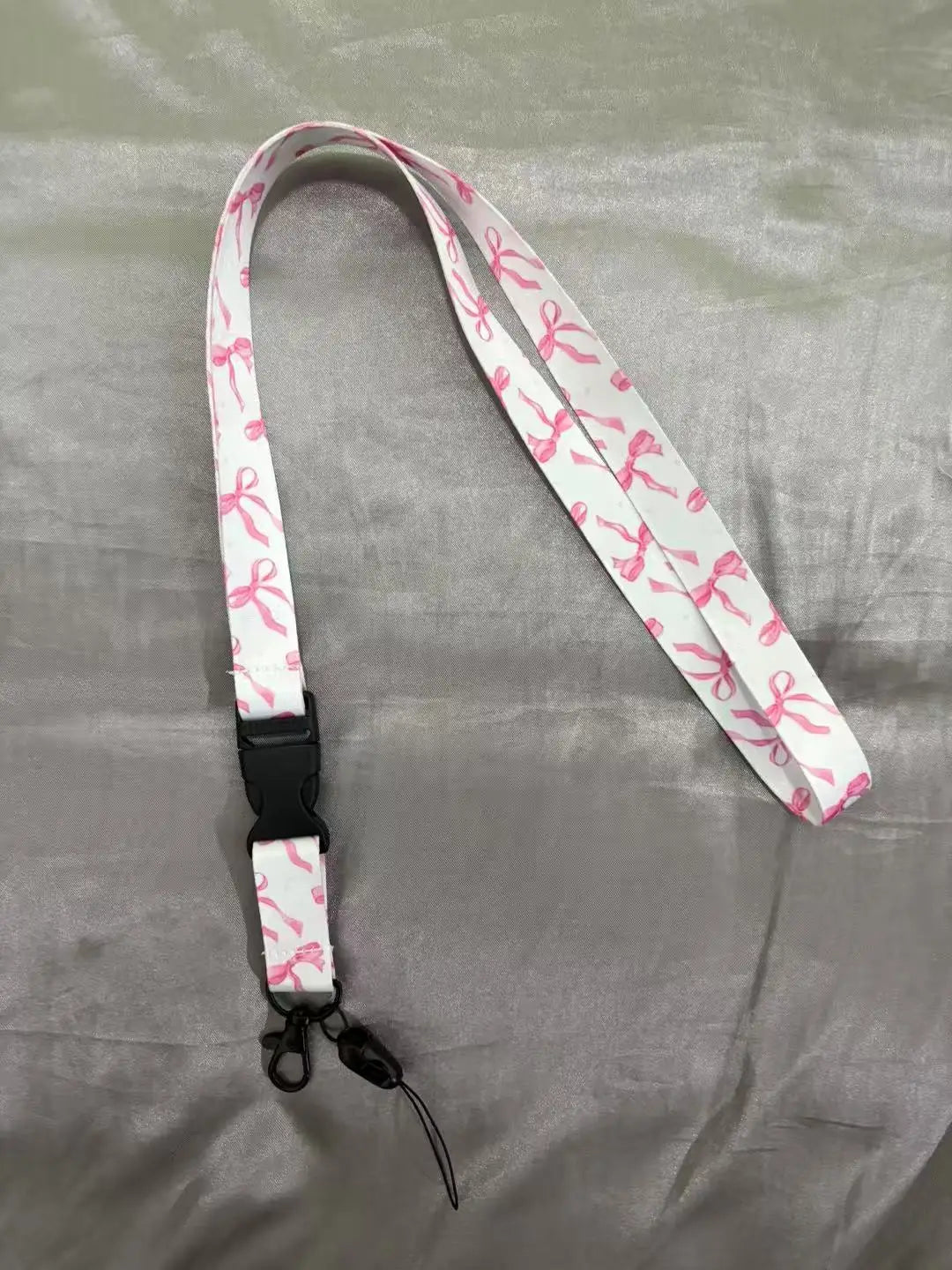 White lanyard with pink floral print and black clip attached