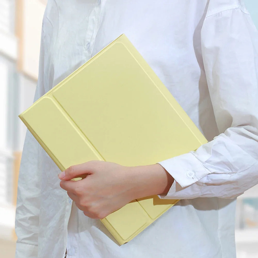 Una persona sostiene una funda de teclado Bluetooth amarilla desmontable para un iPad.